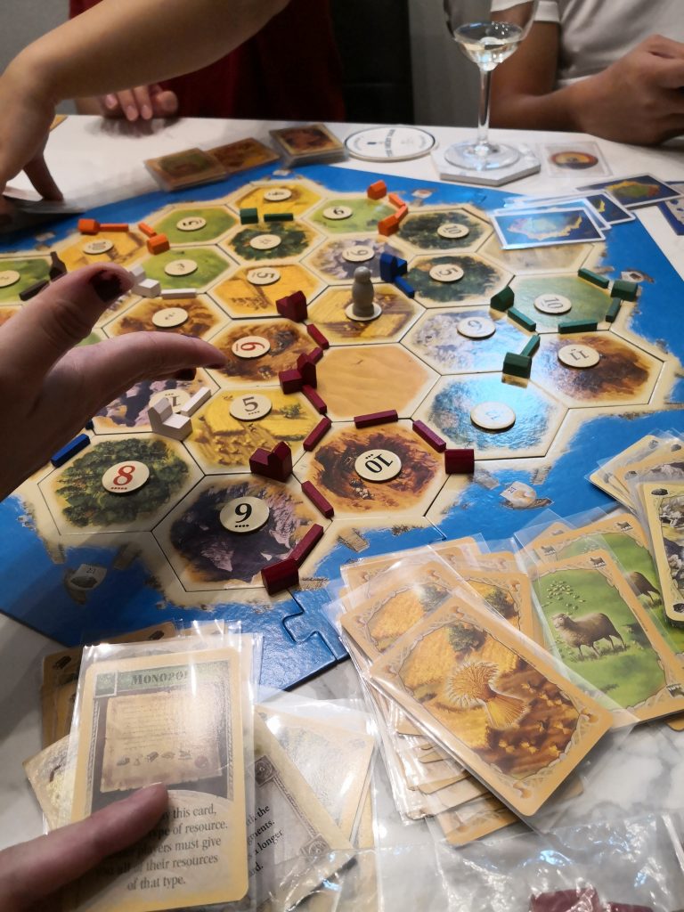 The GF (to my left) probably wanting to wreck my settlements after I played the Monopoly card to grab everyone's wheat even after I had a natural wheat monopoly.